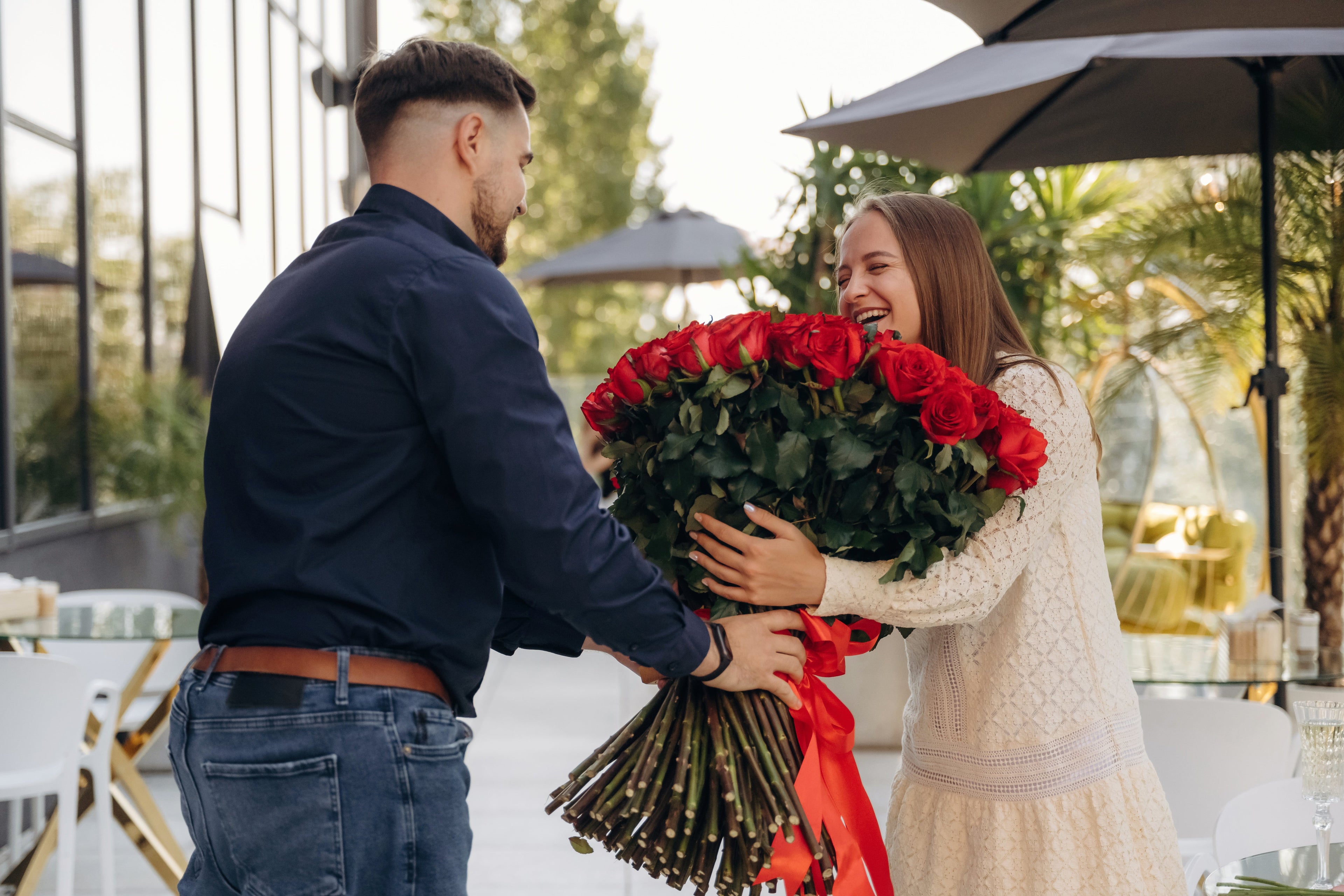 Man giving large bouquet of red roses to happy woman