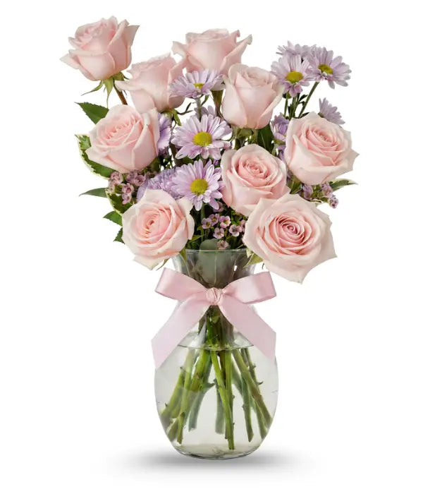 Pink bouquet of roses, daisies, waxflower, carnations and pittosporum in a vase with a pink bow on it
