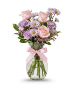 Pink bouquet of roses, daisies, waxflower, carnations and pittosporum in a vase with a pink bow on it