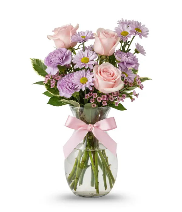 Pink bouquet of roses, daisies, waxflower, carnations and pittosporum in a vase with a pink bow on it